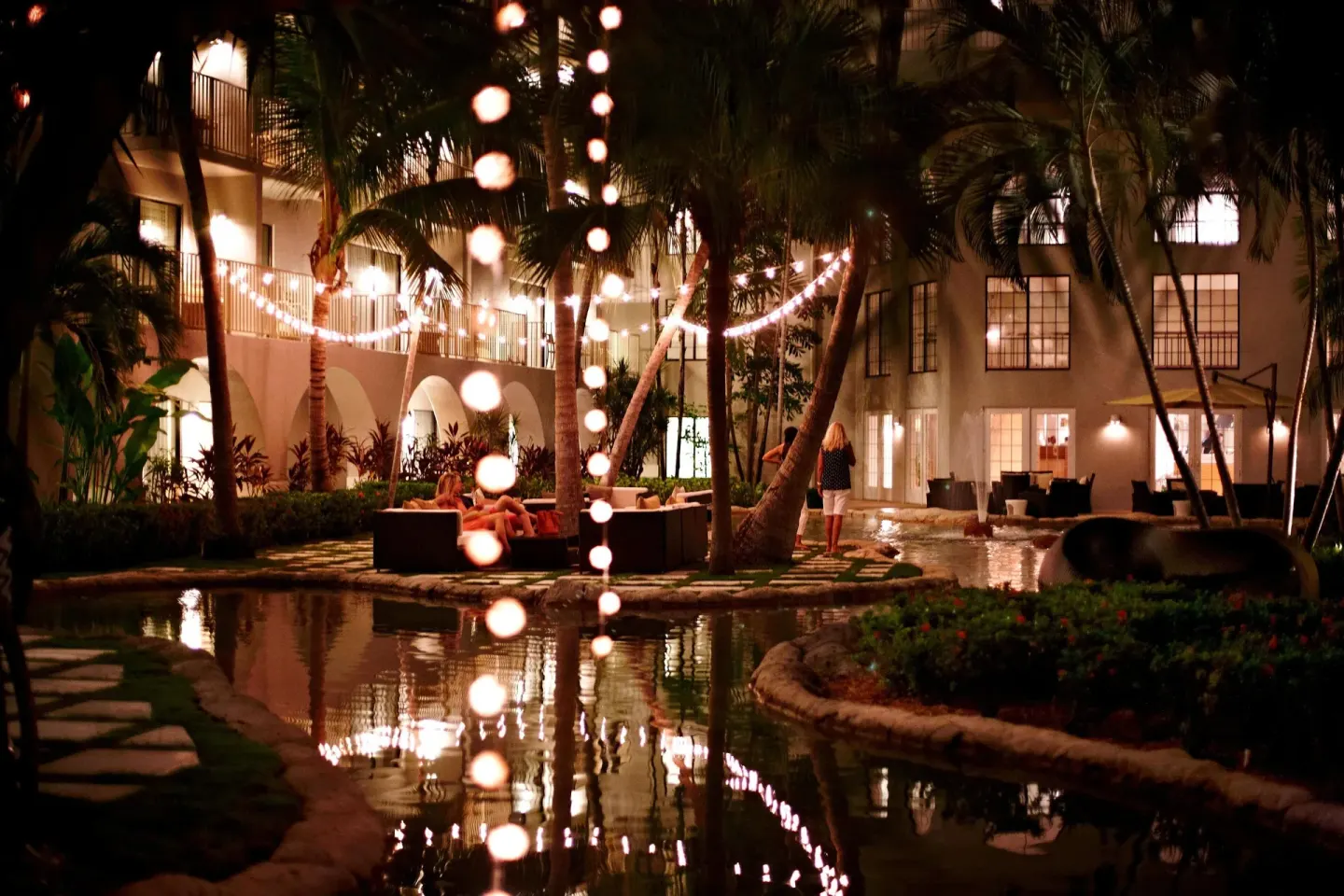 Nighttime courtyard with palms, string lights and water at Grand Cayman Marriott Resort.