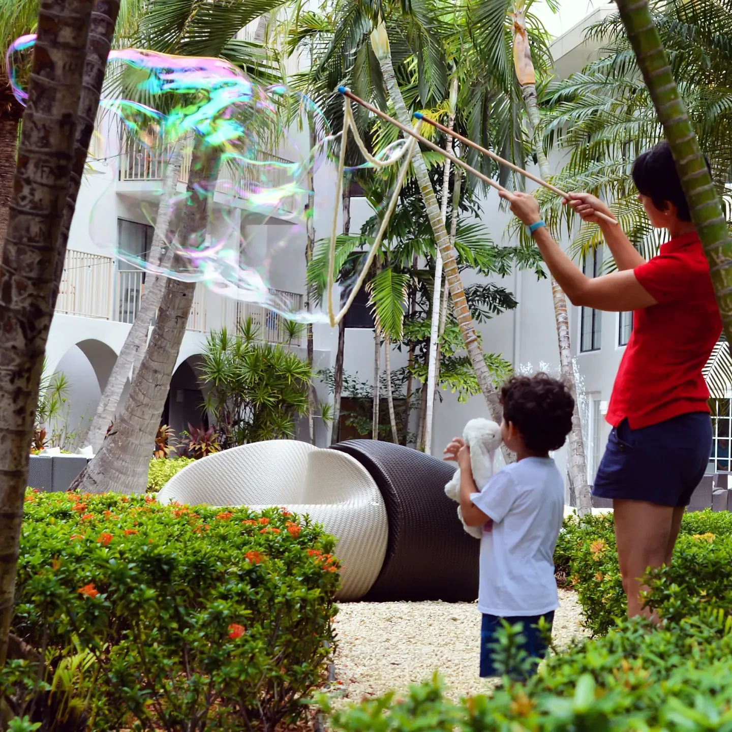 Child watching large bubbles in a palm-filled courtyard at Grand Cayman Marriott Resort.