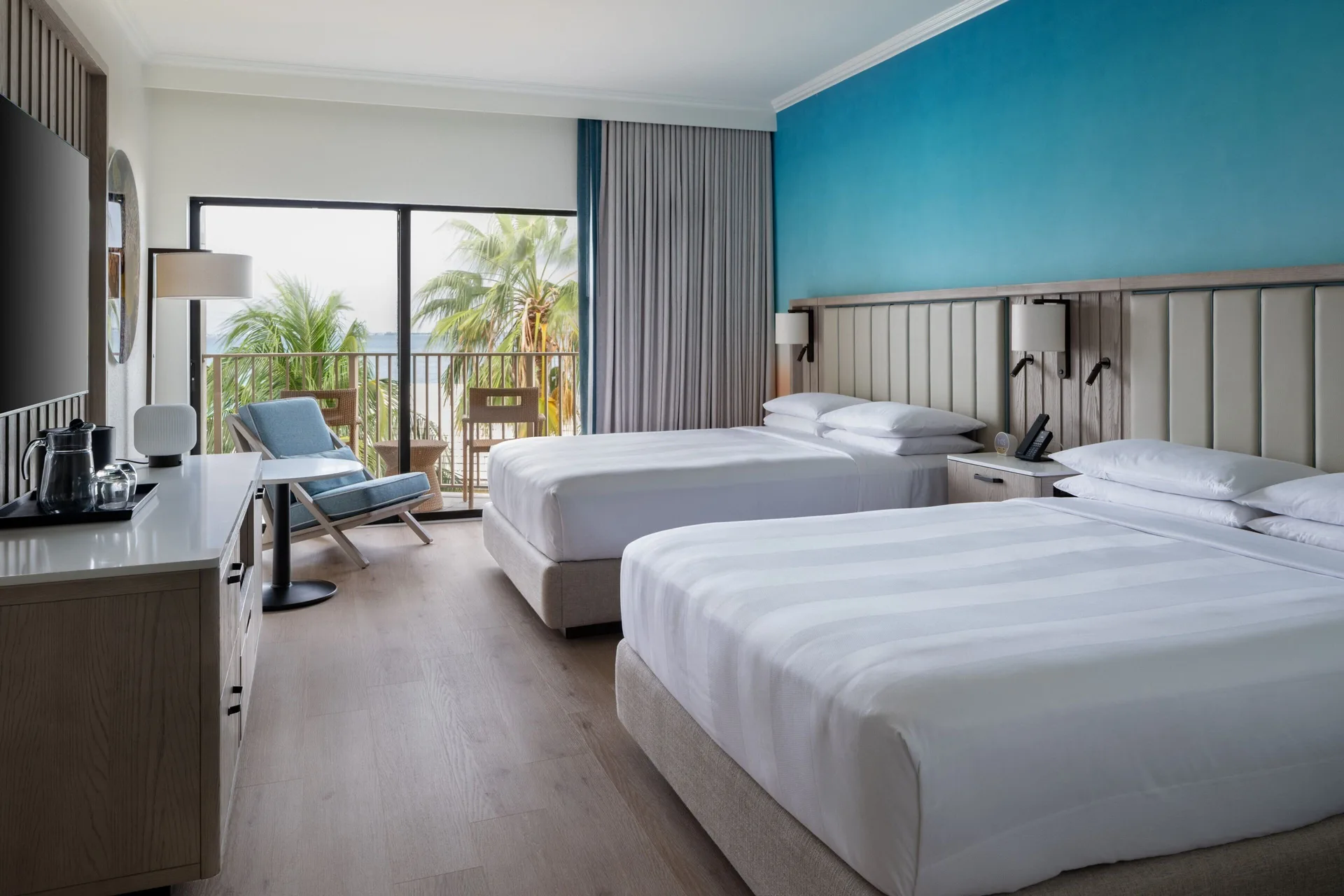 Guest room with two queen beds and balcony palms at Grand Cayman Marriott Resort.