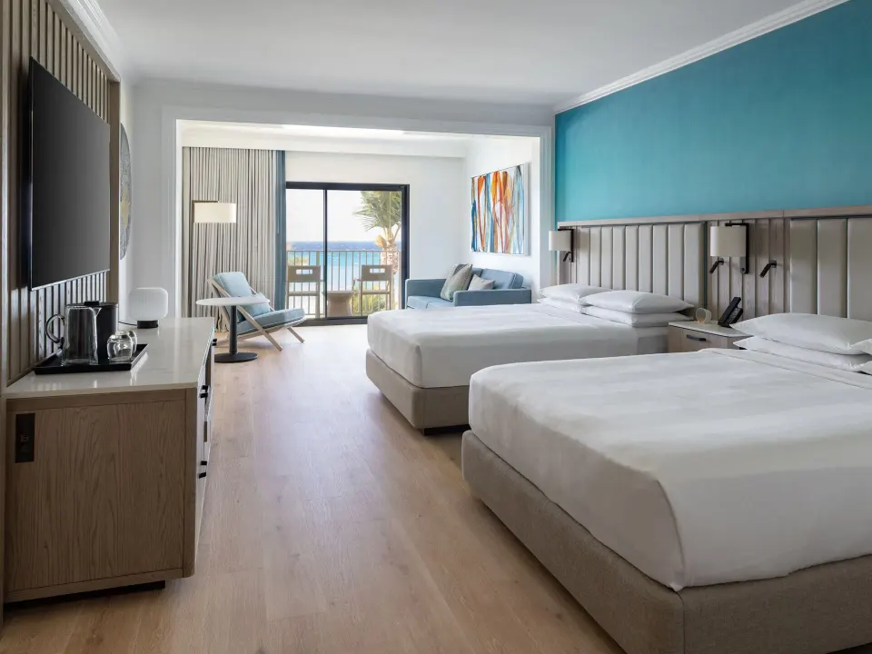 Junior suite with two beds and ocean-facing balcony at Grand Cayman Marriott Resort.