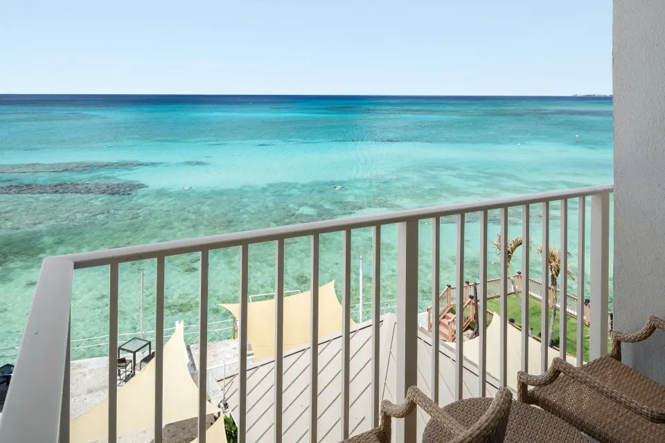 Junior suite balcony with wicker chairs and ocean view at Grand Cayman Marriott Resort.