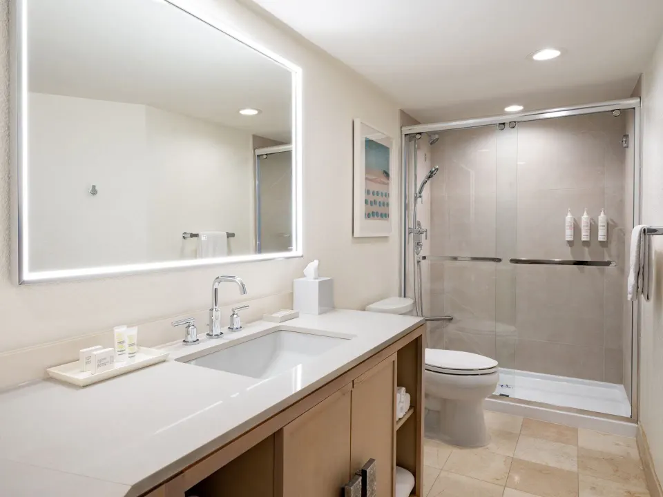 Guest room bathroom with vanity and glass shower at Grand Cayman Marriott Resort.