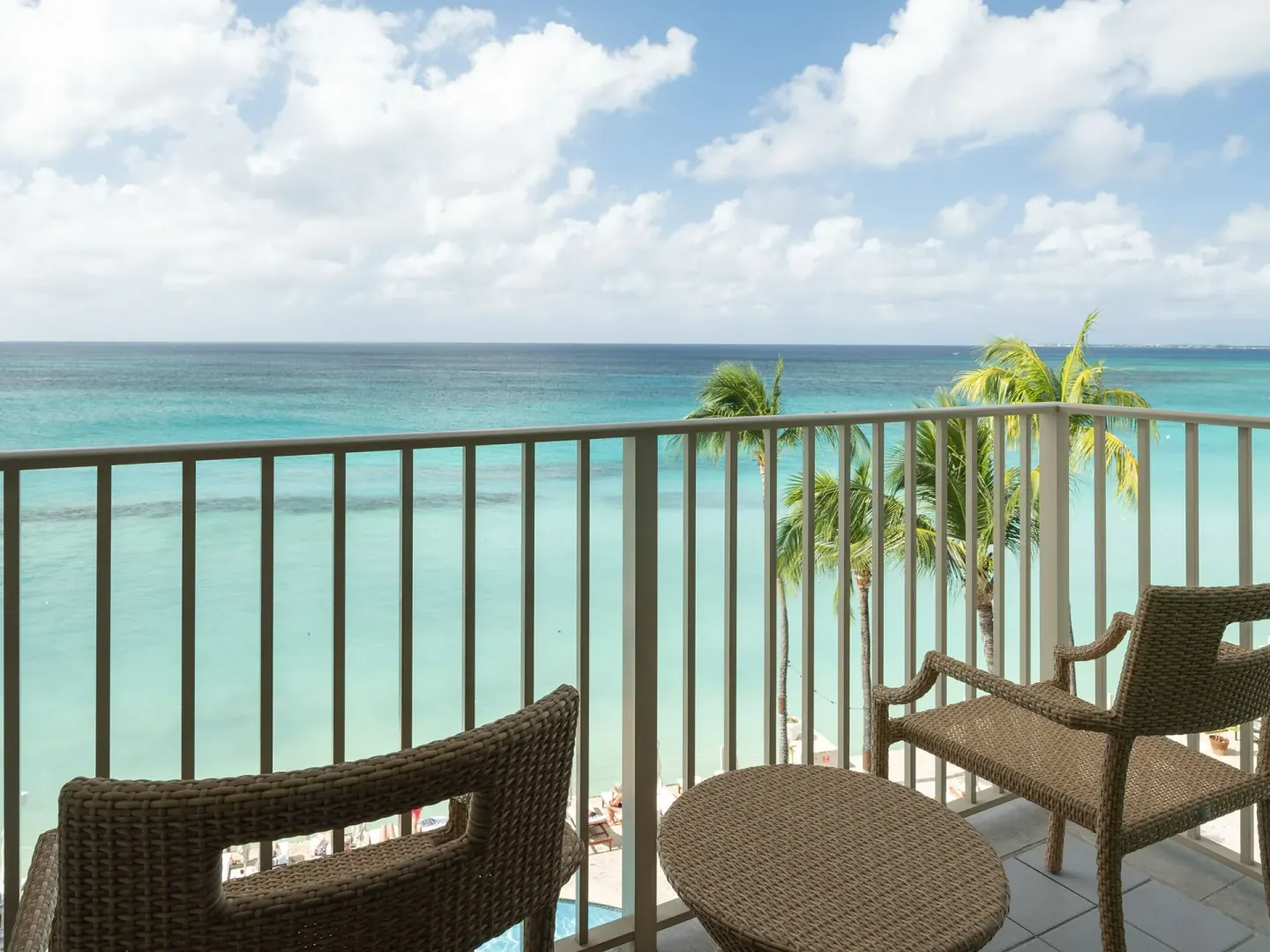 Oceanfront balcony with wicker seating and Caribbean Sea views at Grand Cayman Marriott Resort.