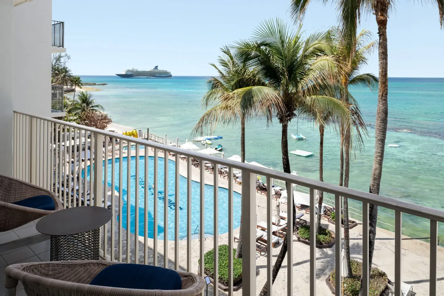 Oceanfront balcony with pool, palms, and turquoise sea at Grand Cayman Marriott Resort.