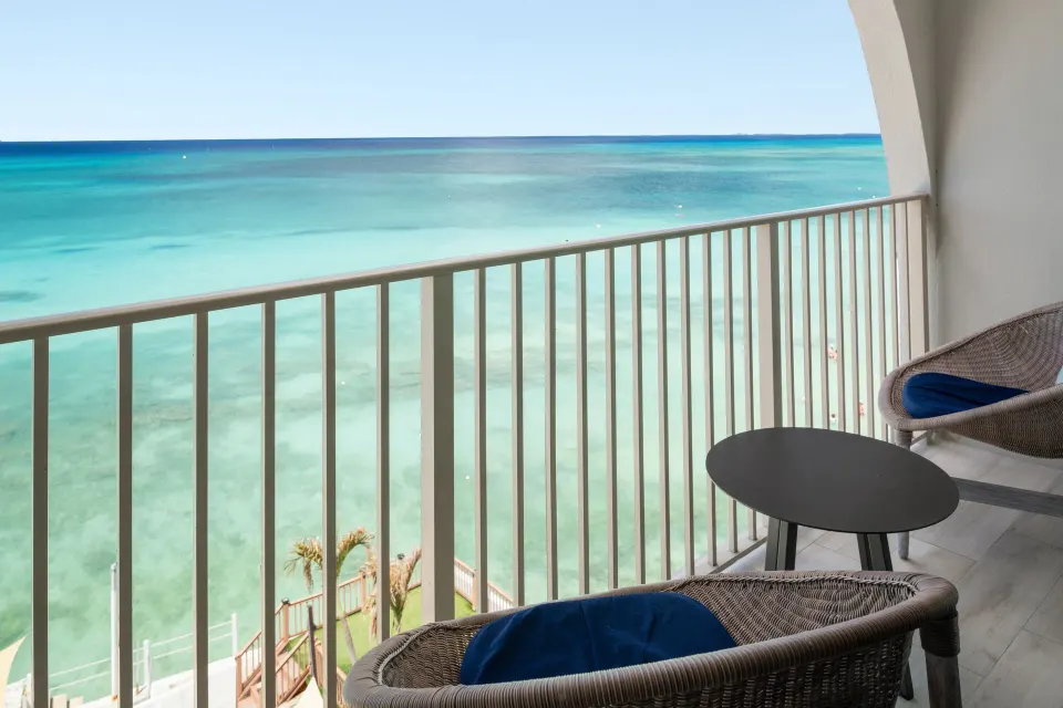 Oceanfront suite balcony with chairs and turquoise sea at Grand Cayman Marriott Resort.