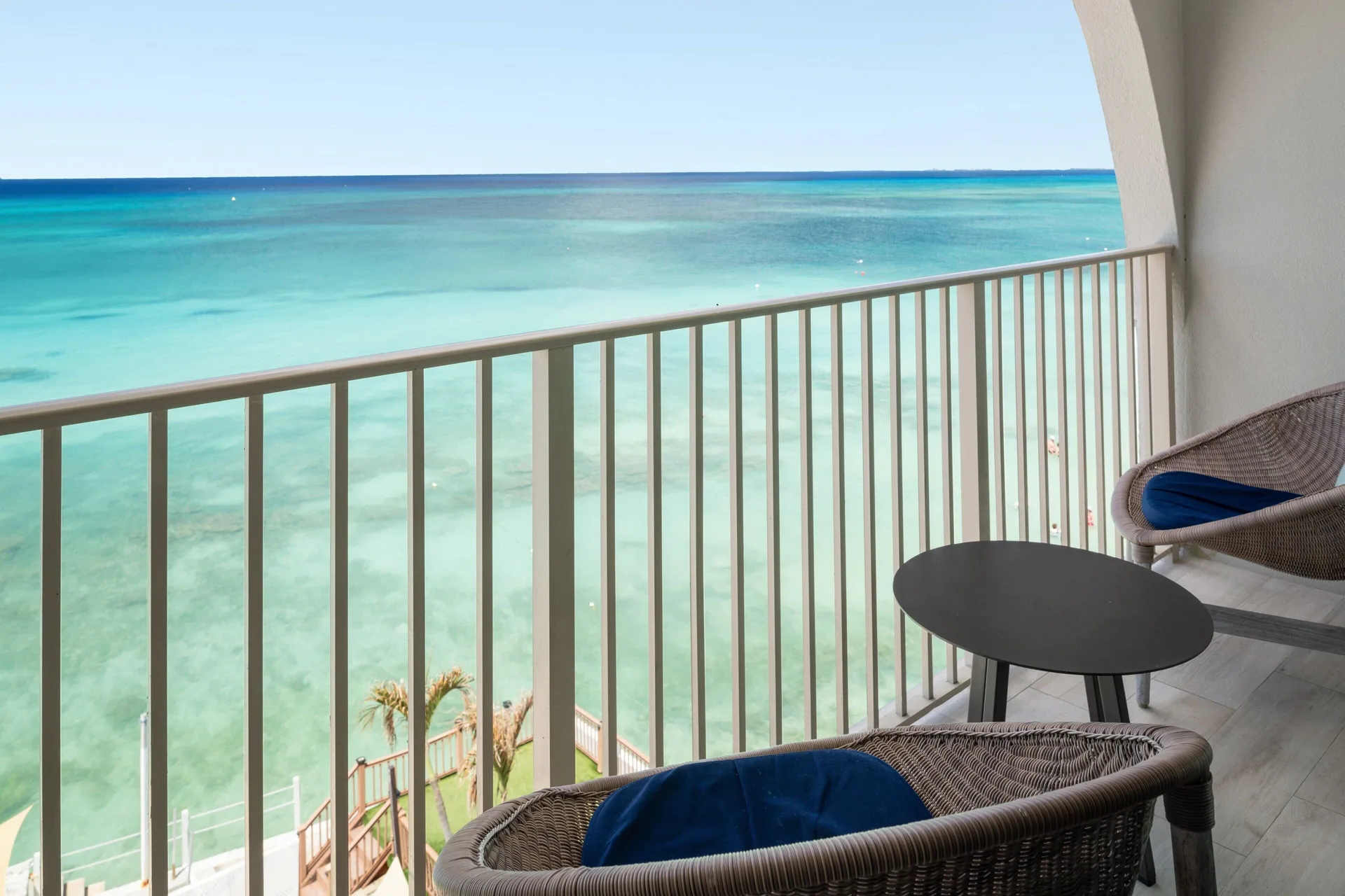 Oceanfront suite balcony with chairs and turquoise sea at Grand Cayman Marriott Resort.