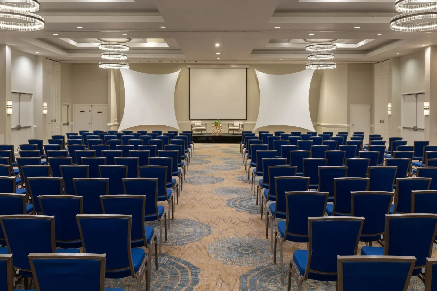 Ballroom set with rows of blue chairs facing a stage at Grand Cayman Marriott Resort.