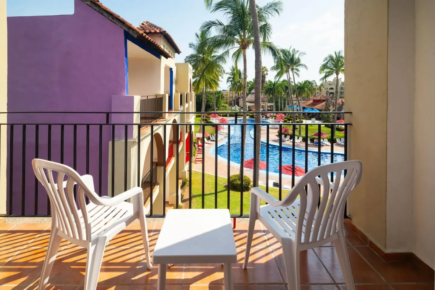 Balcony with two chairs overlooking the pool and palms at Grand Decameron Complex Bucerias.