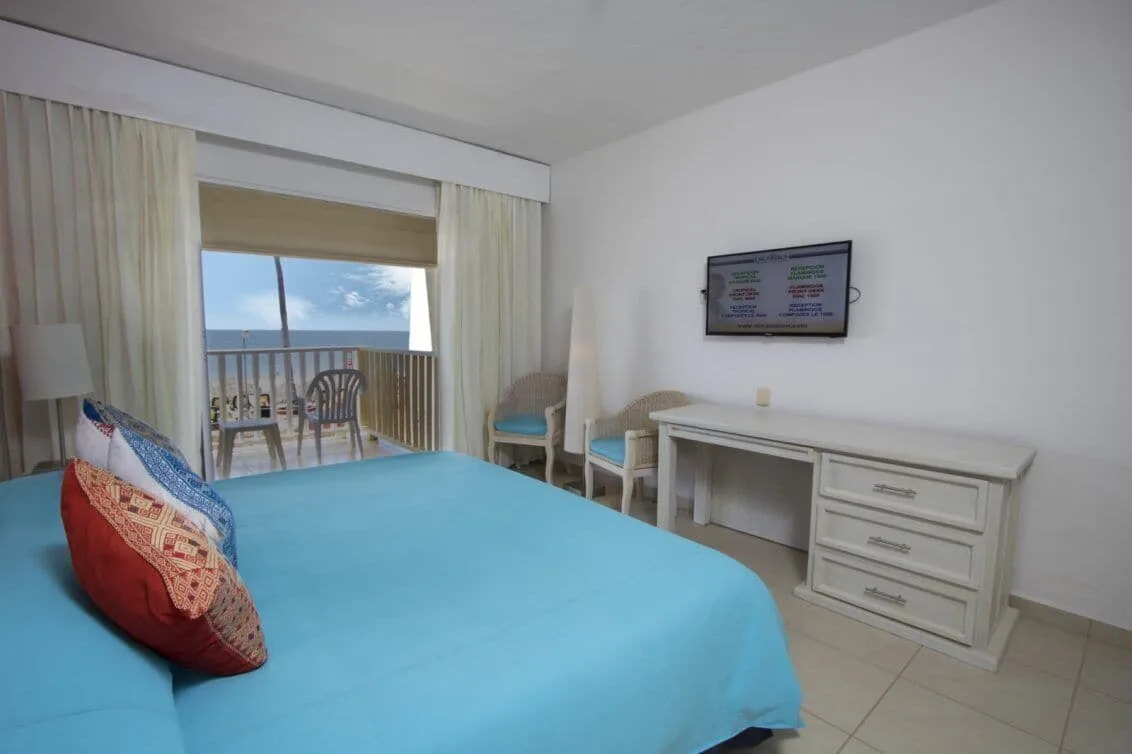 Ocean-facing guest room with blue king bed and balcony at Grand Decameron Complex Bucerias.