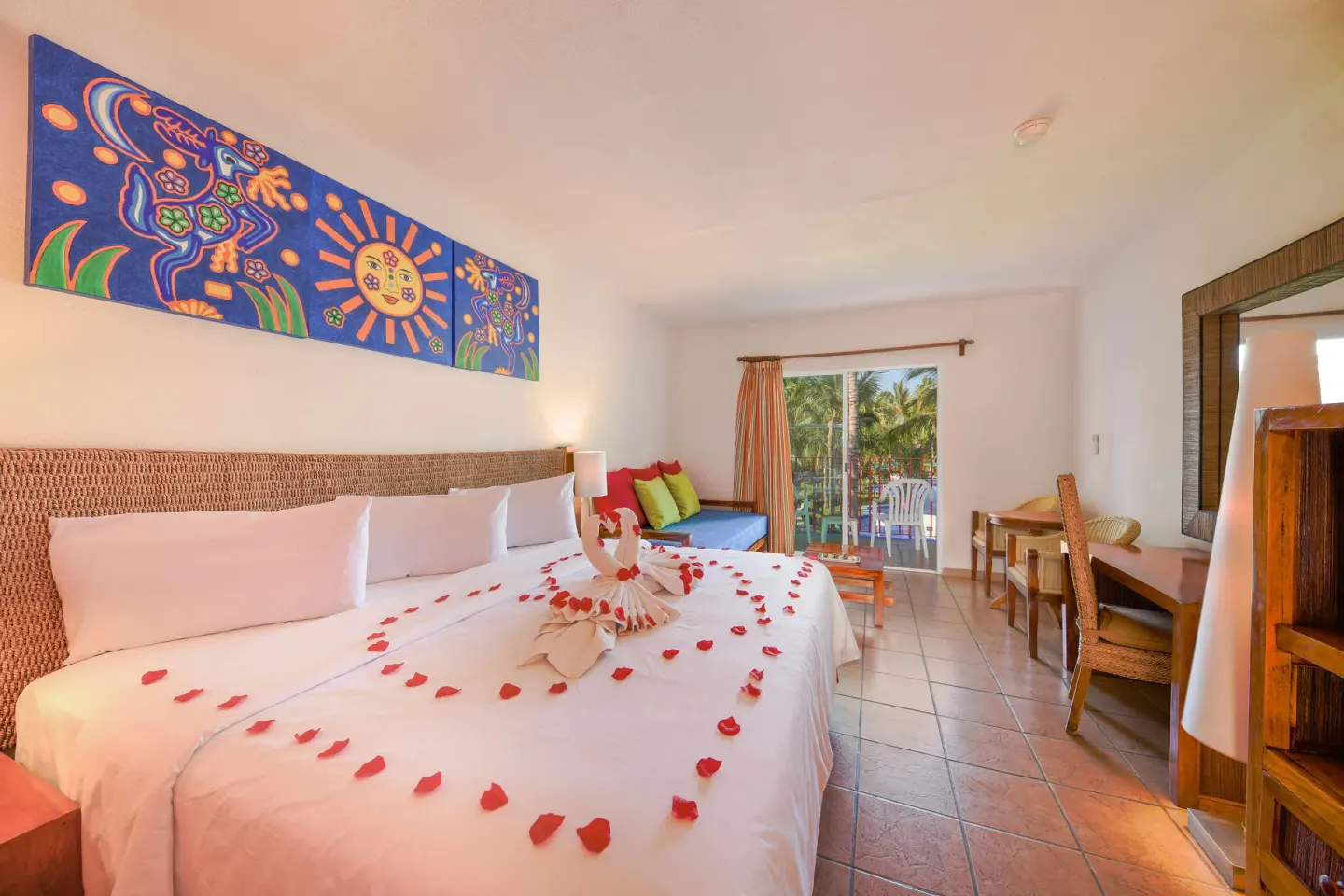 King bed decorated with petals and towel swans at Grand Decameron Complex Bucerias.
