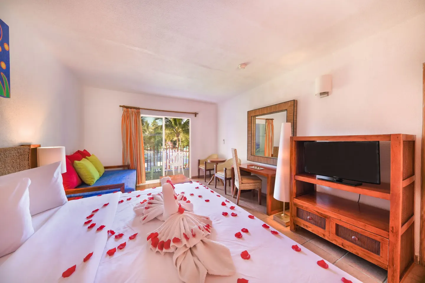 Guest room with king bed, towel swans, balcony and TV at Grand Decameron Complex Bucerias.