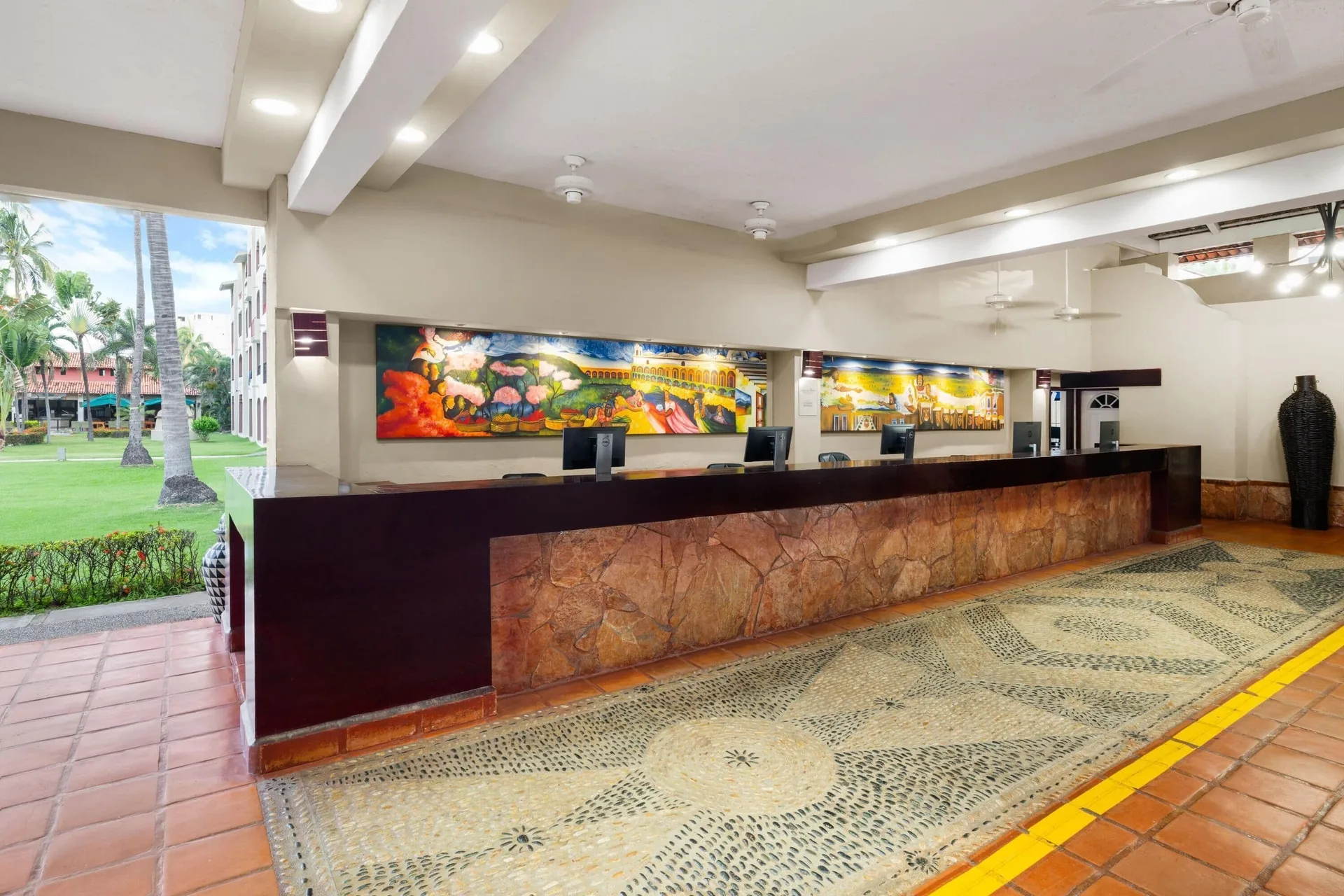 Open-air lobby front desk beside gardens at Grand Decameron Complex Bucerias.