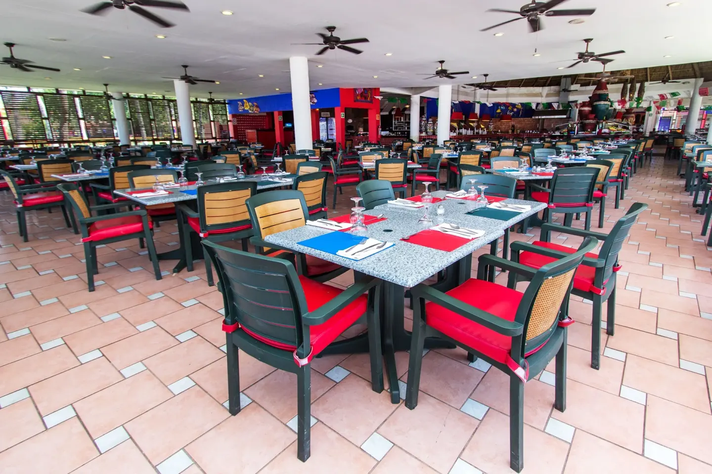 Large casual dining room with red-cushioned chairs at Grand Decameron Complex Bucerias.