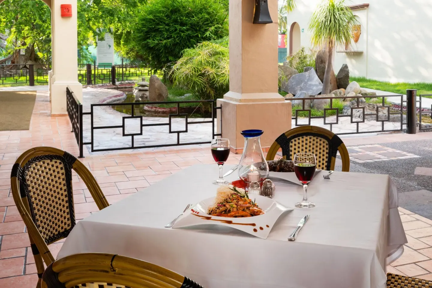 Covered patio table set with plated pasta and wine at Grand Decameron Complex Bucerias.