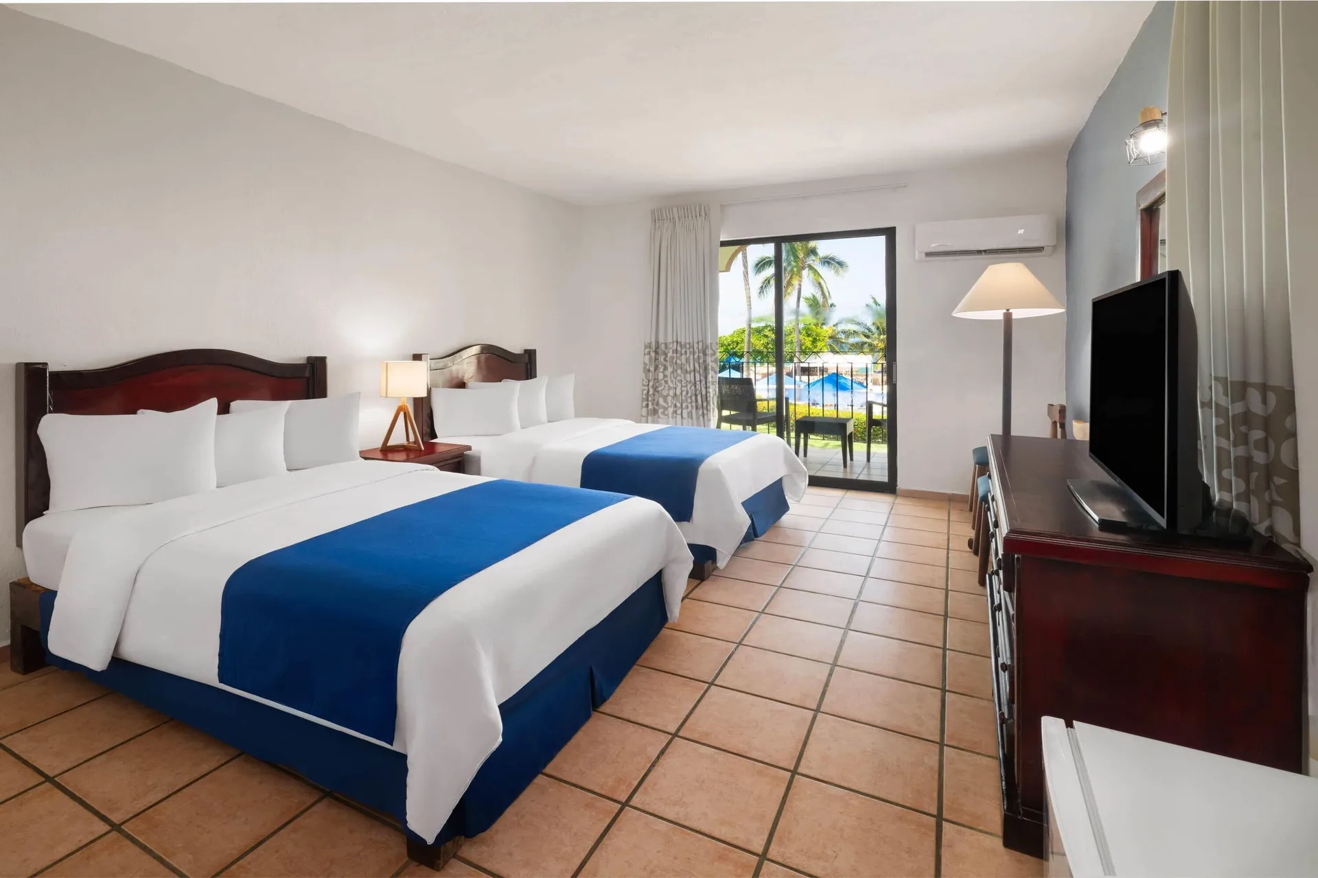 Ocean View room with two double beds, balcony, and TV at Grand Decameron Complex Bucerias.
