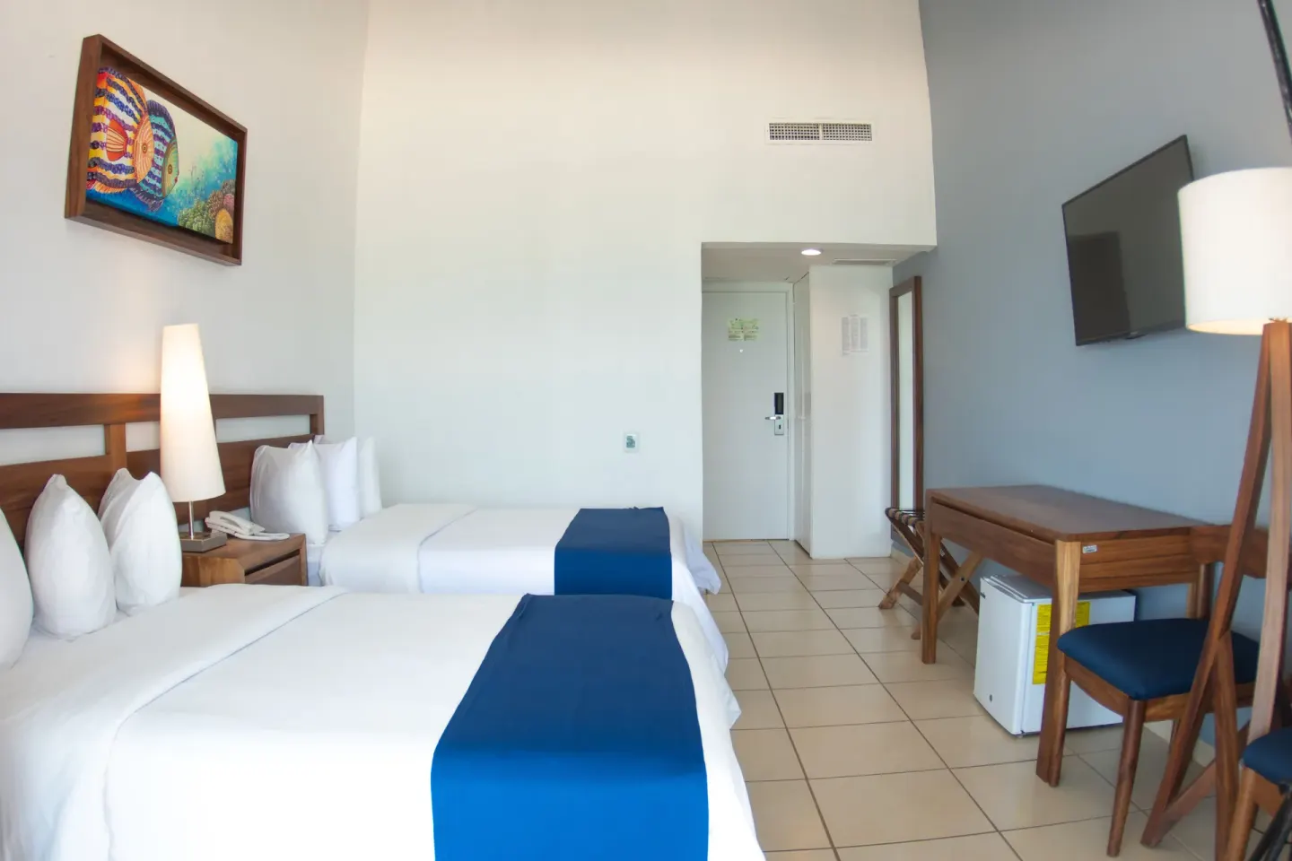 Ocean View room with two double beds, desk, and wall TV at Grand Decameron Complex Bucerias.