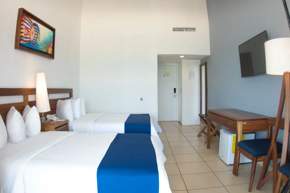 Ocean View room with two double beds, desk, and wall TV at Grand Decameron Complex Bucerias.