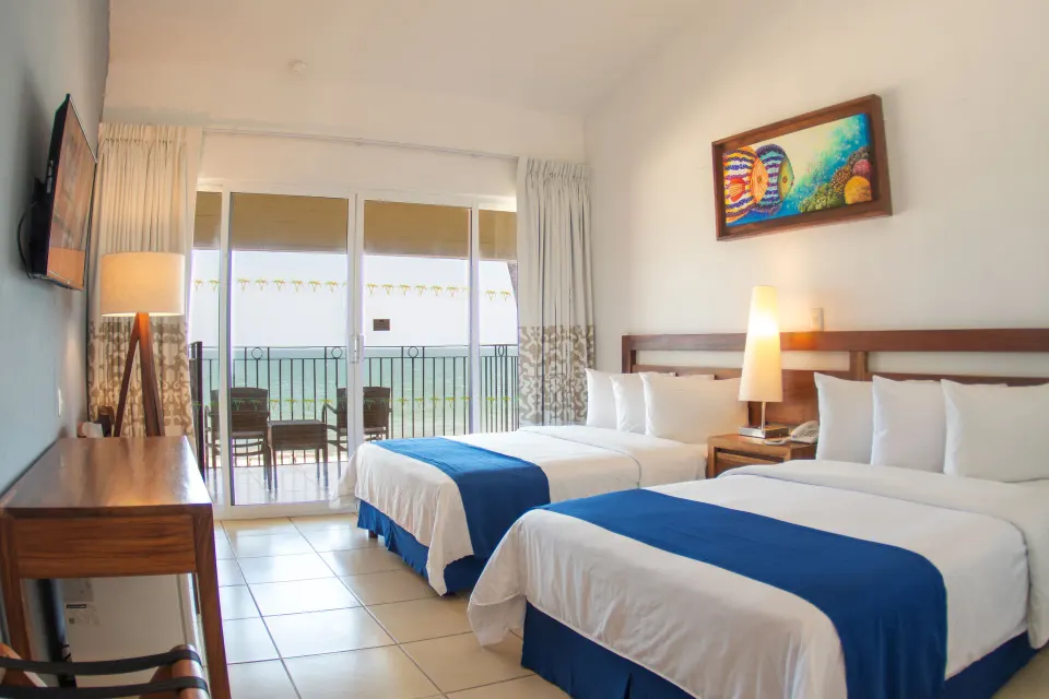 Ocean View room with two double beds and balcony doors at Grand Decameron Complex Bucerias.