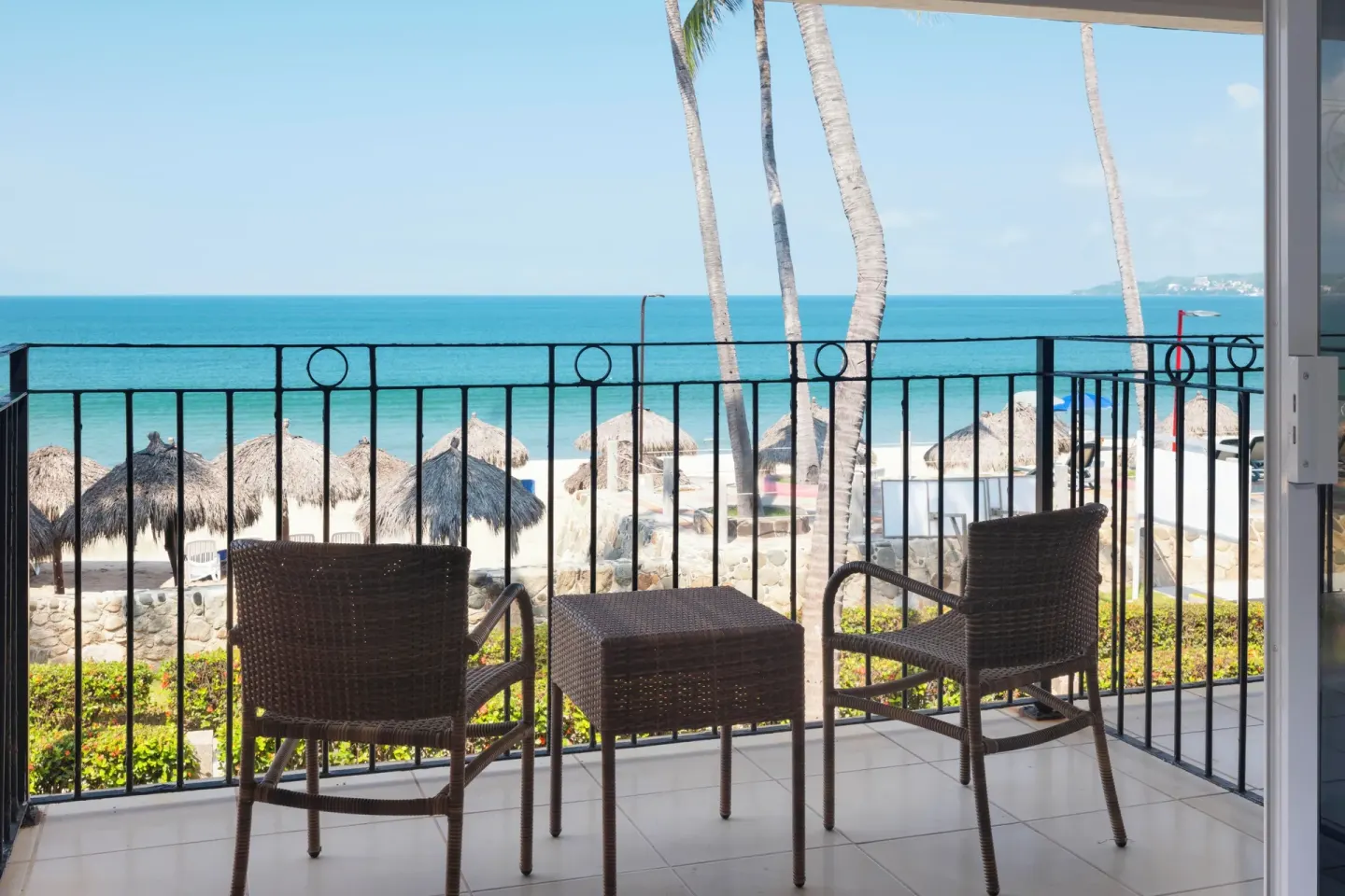 Oceanfront balcony seating with palm trees and beach view at Grand Decameron Complex Bucerias.