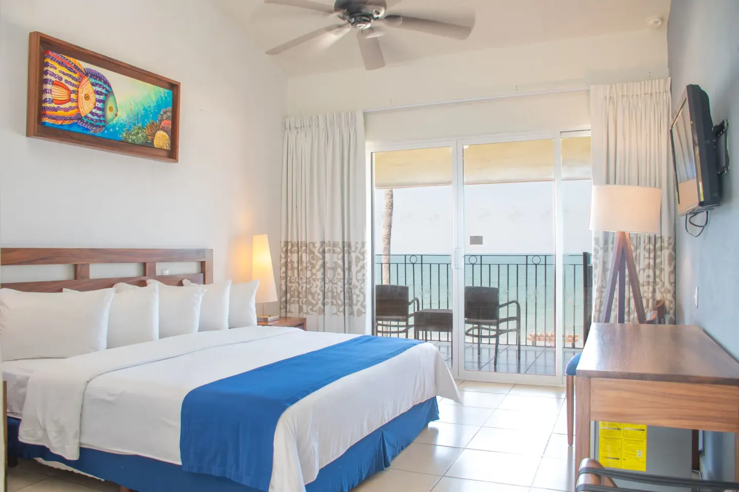 Oceanfront room with one bed and balcony chairs at Grand Decameron Complex Bucerias.