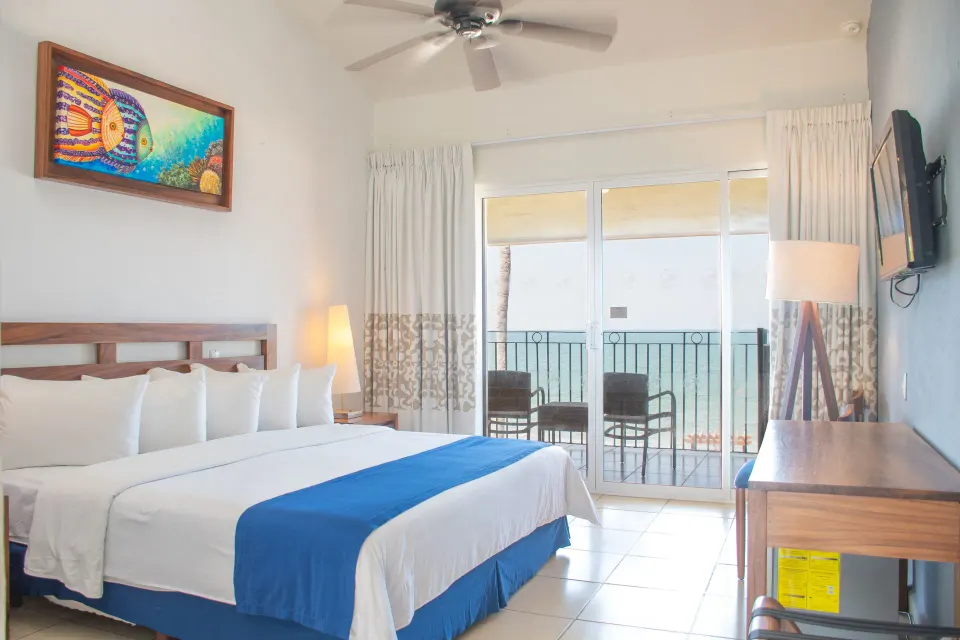 Oceanfront room with one bed and balcony chairs at Grand Decameron Complex Bucerias.