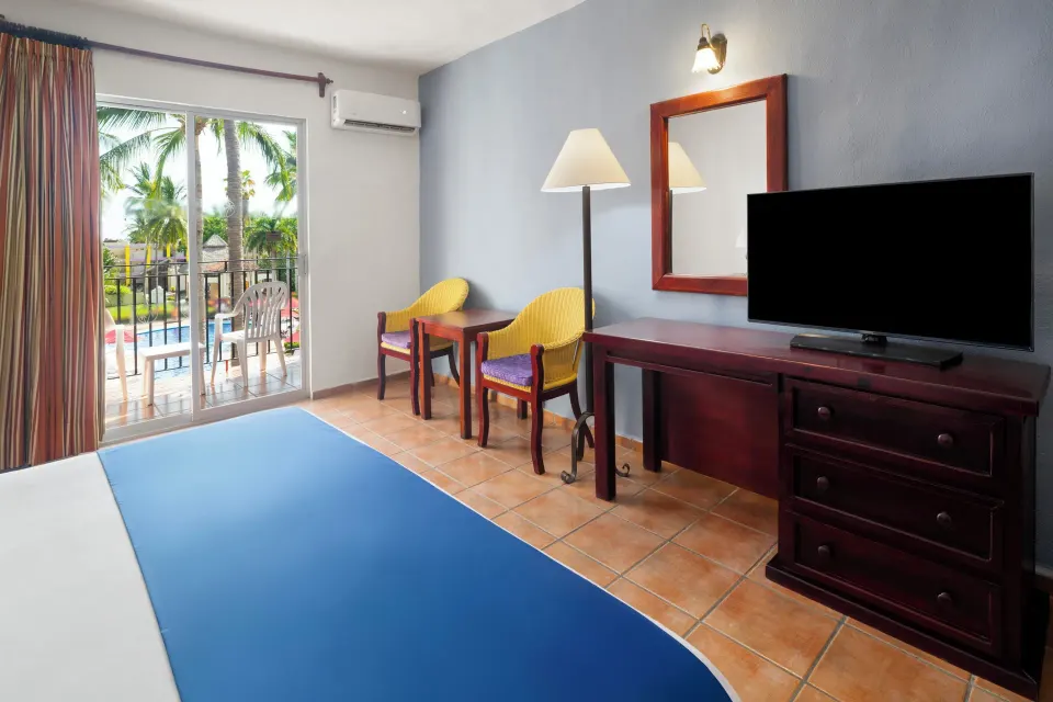 Standard Room seating area, TV, and balcony at Grand Decameron Complex Bucerias.