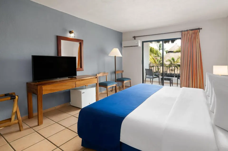 Standard Room with king bed, TV, and balcony at Grand Decameron Complex Bucerias.