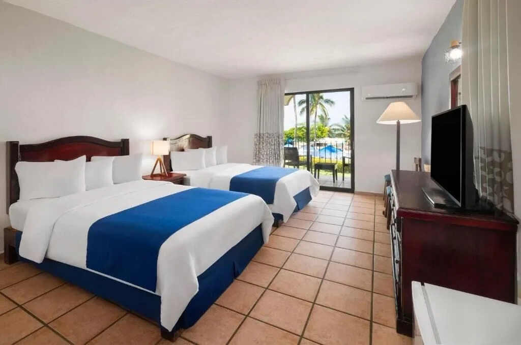 Standard Room with two beds, TV, and pool-view patio at Grand Decameron Complex Bucerias.