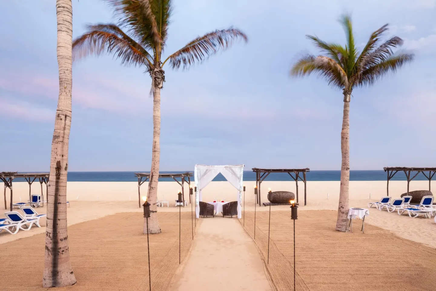 Beach dining canopy between palm trees at Grand Decameron Los Cabos.