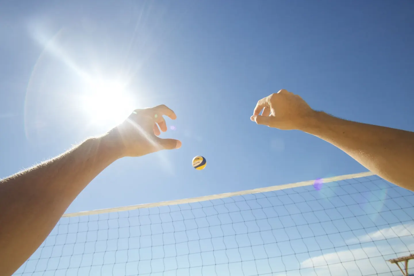 Beach volleyball net and ball under bright sun at Grand Decameron Los Cabos.