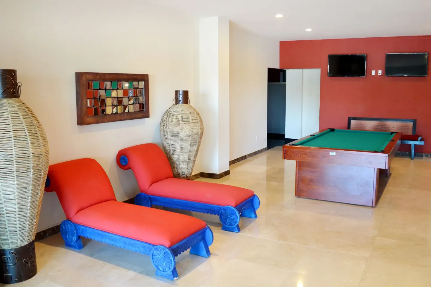 Game room with pool table and red lounge chairs at Grand Decameron Los Cabos.