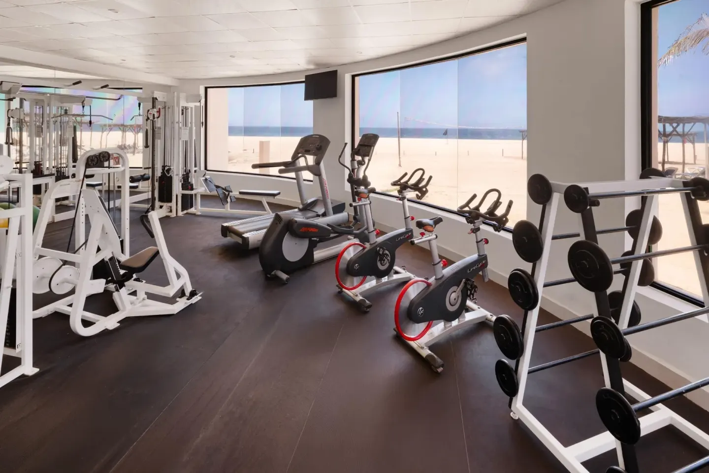 Gym with bikes, treadmill, weights, and ocean-facing windows at Grand Decameron Los Cabos.