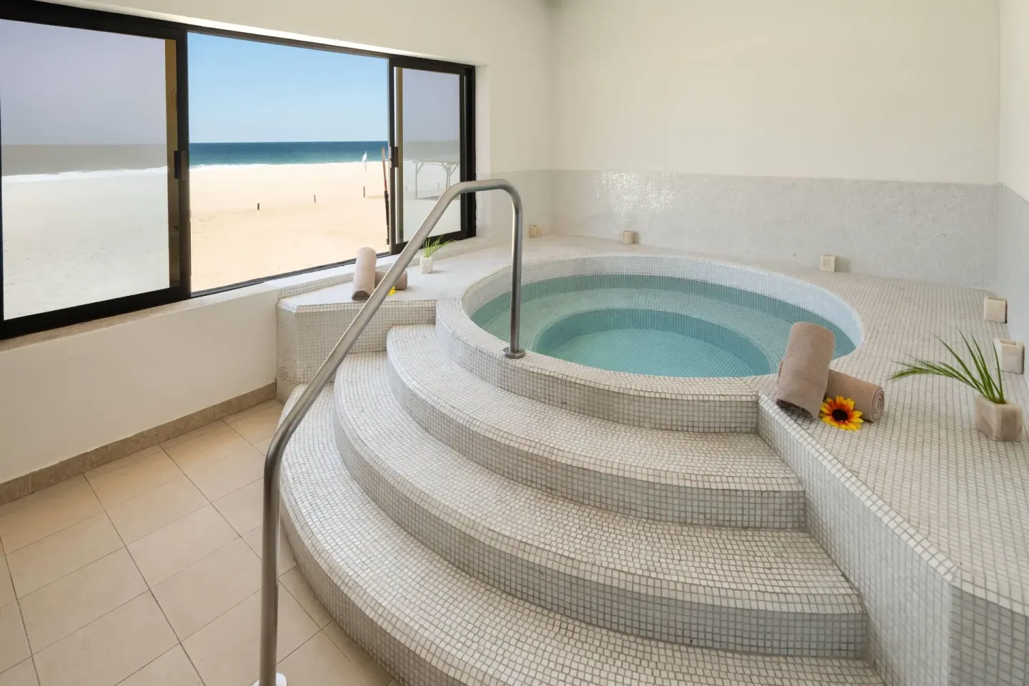 Indoor spa whirlpool with mosaic tile steps and beach view at Grand Decameron Los Cabos.