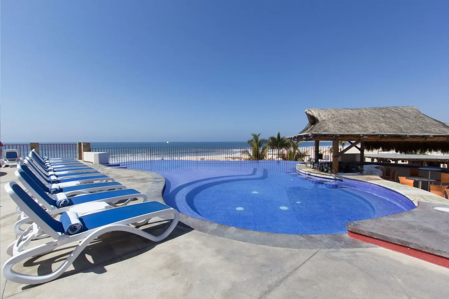 Small ocean-view pool with blue loungers at Grand Decameron Los Cabos.