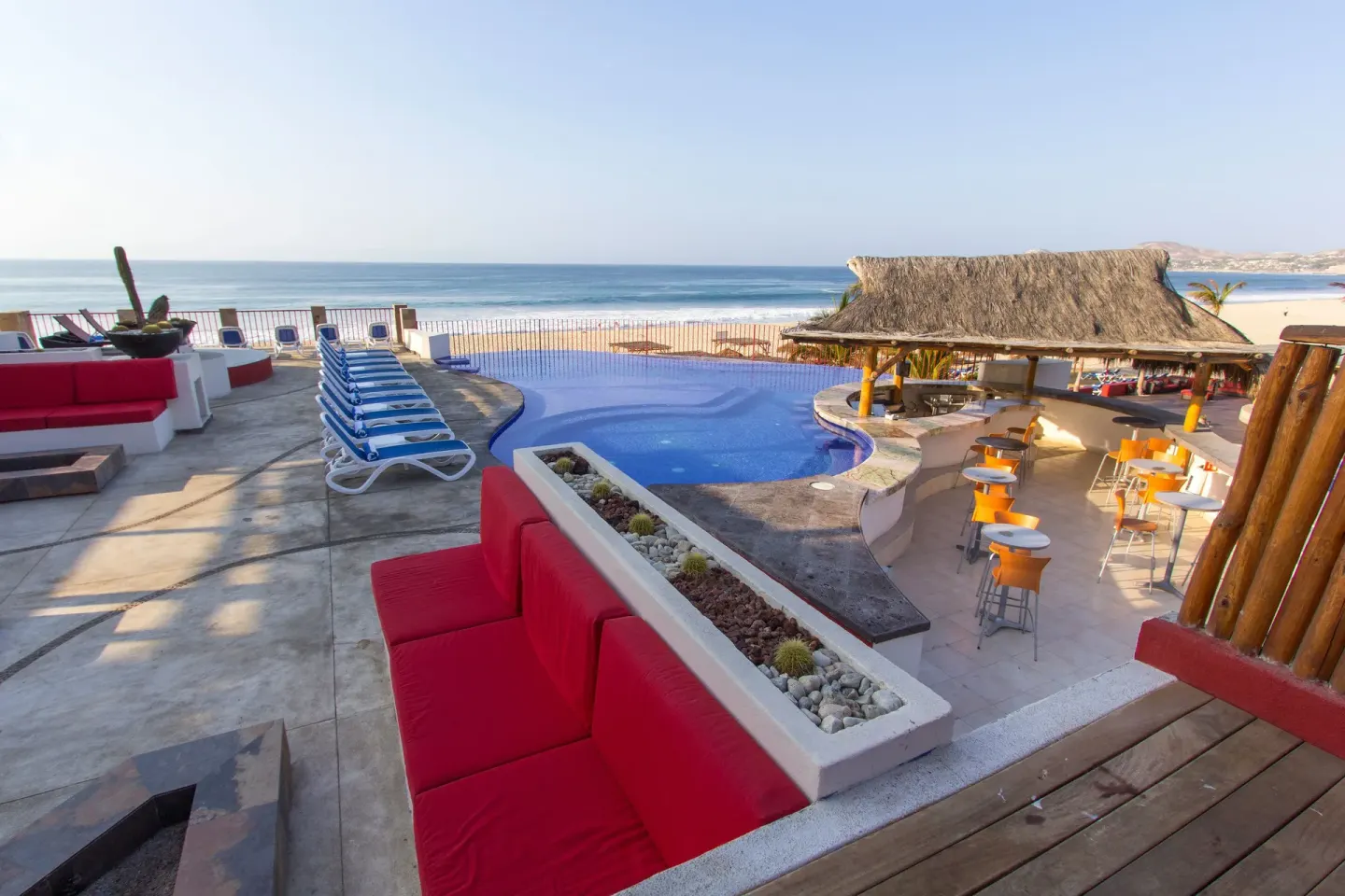 Ocean-view pool terrace with red seating at Grand Decameron Los Cabos.