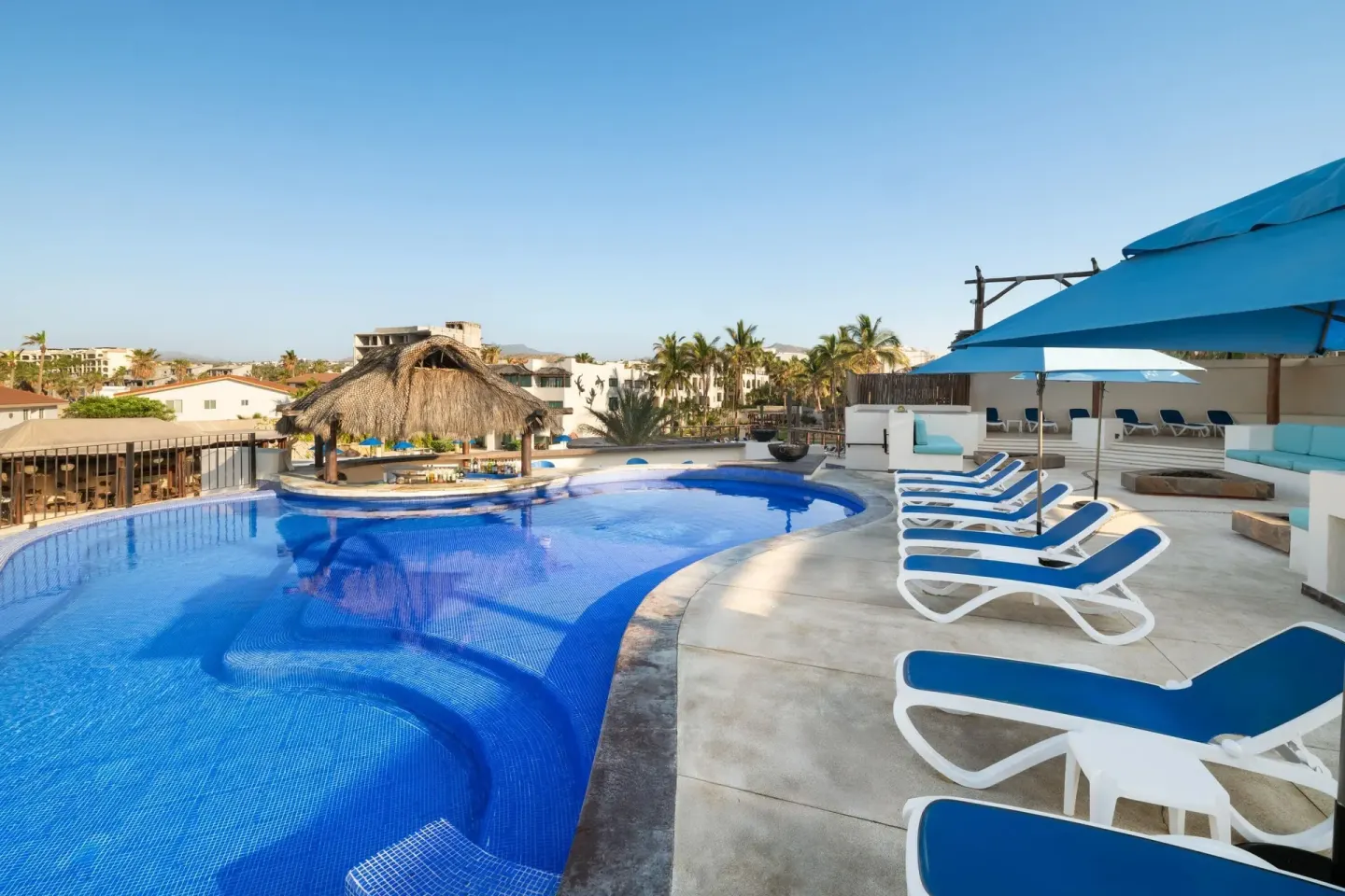 Pool terrace with blue loungers and resort buildings at Grand Decameron Los Cabos.
