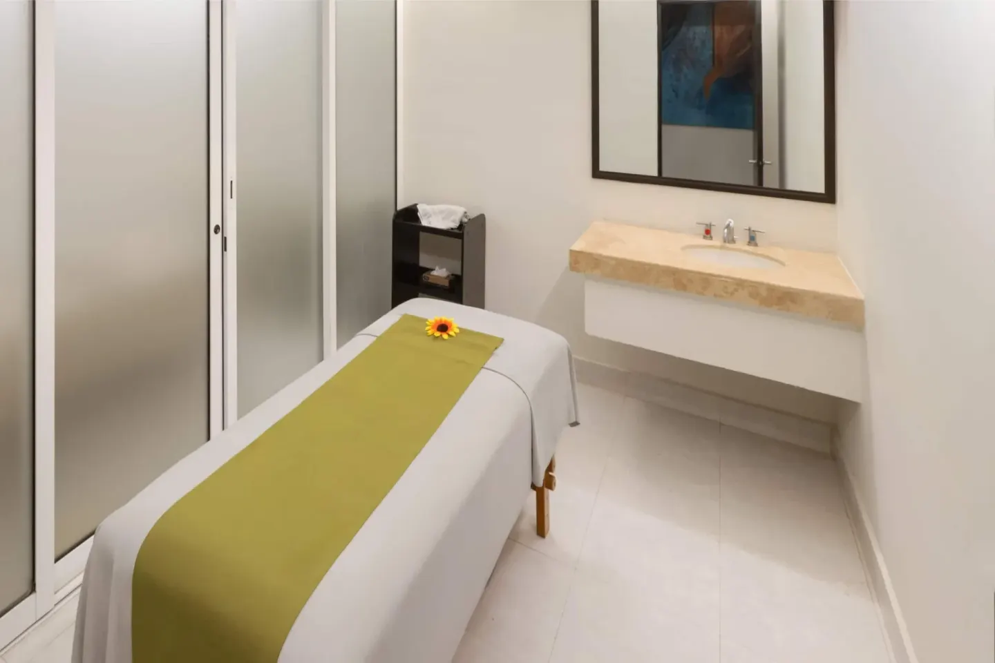 Spa treatment room with massage table and vanity at Grand Decameron Los Cabos.