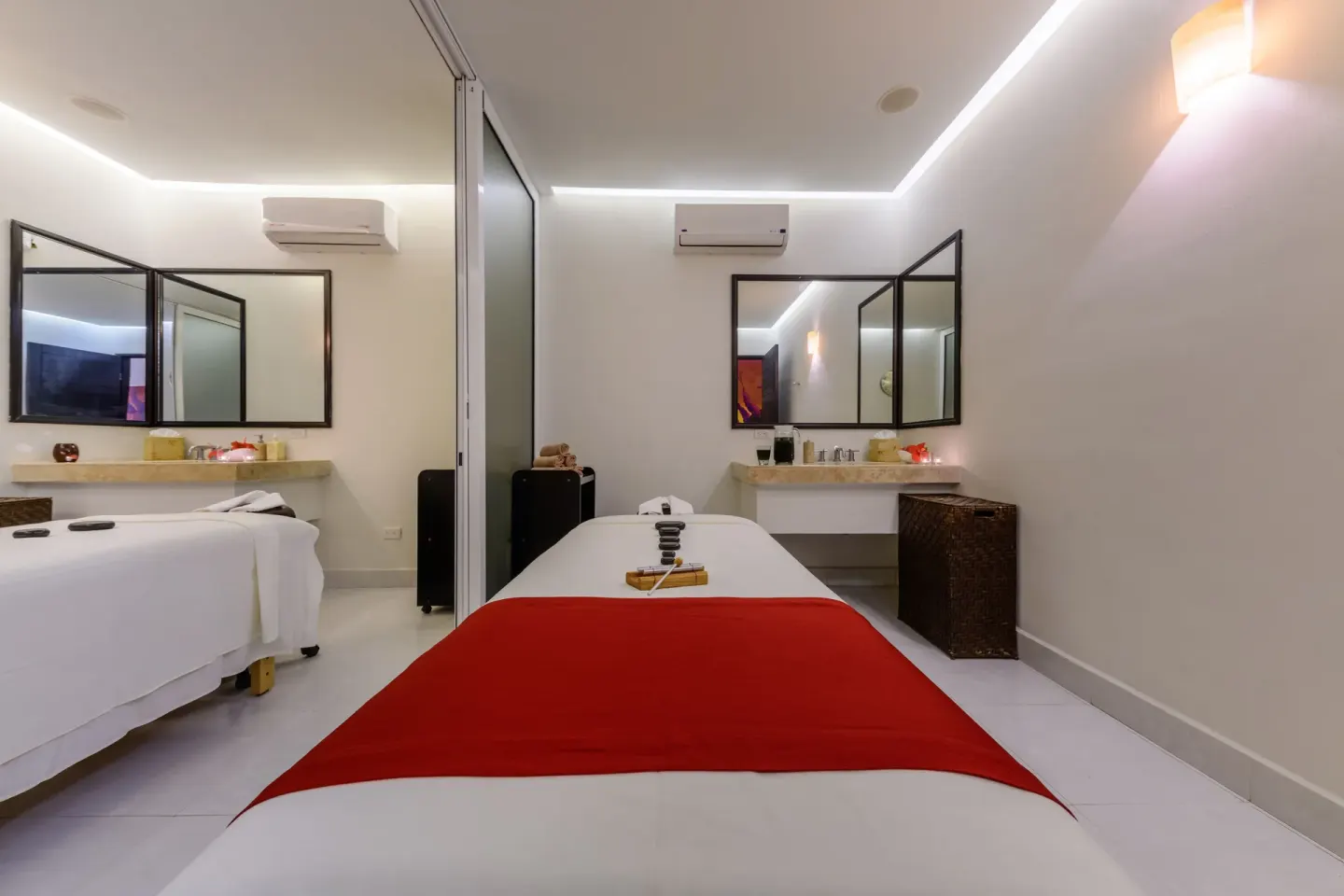 Spa treatment room with a massage bed and red runner at Grand Decameron Los Cabos.