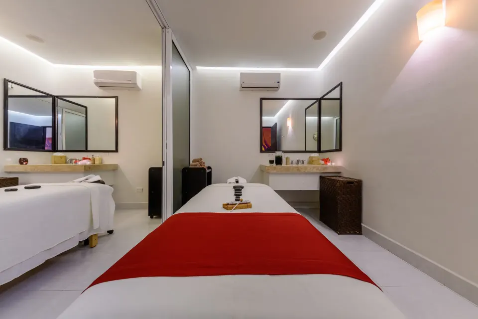 Spa treatment room with a massage bed and red runner at Grand Decameron Los Cabos.