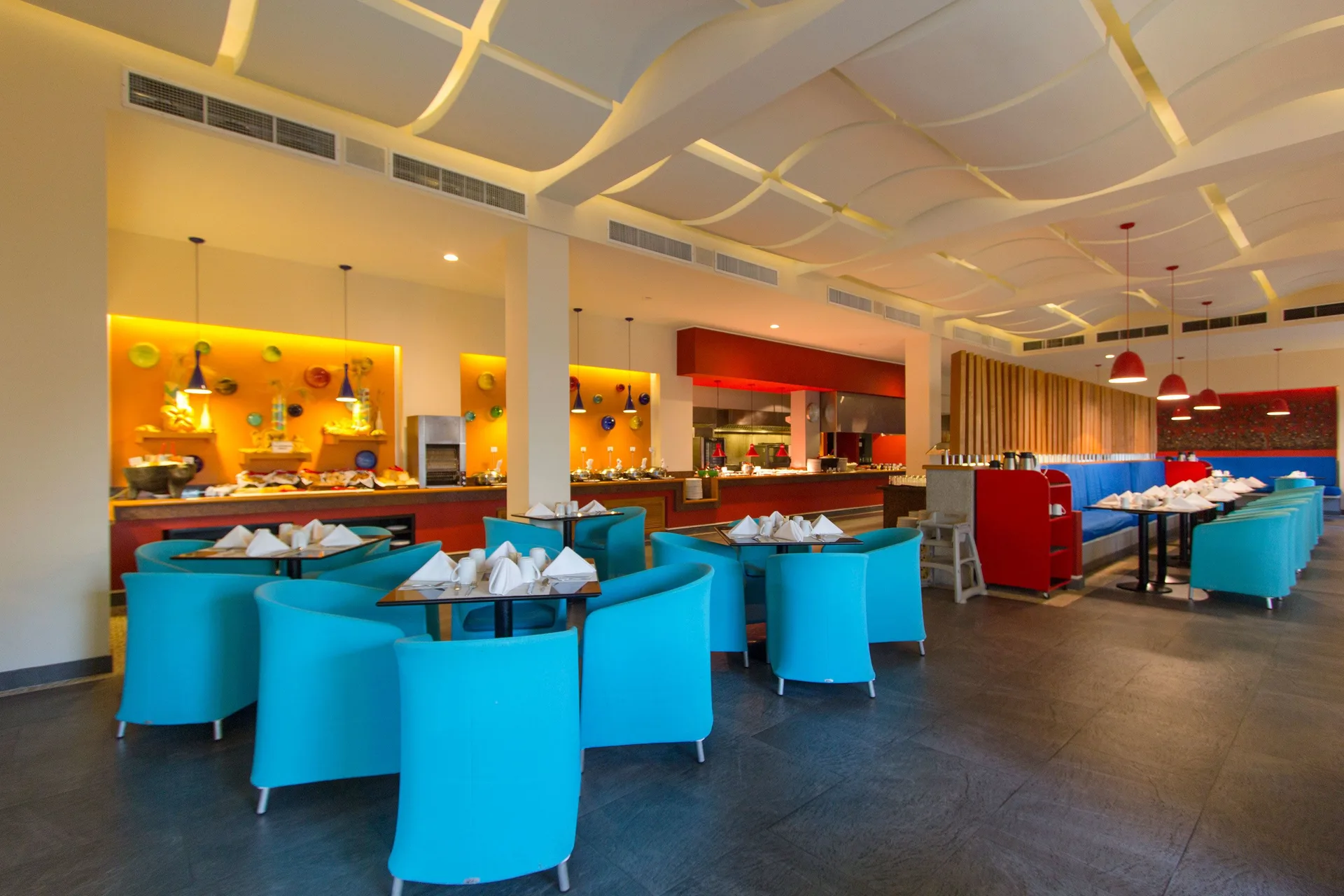 Bright indoor buffet dining room with turquoise chairs at Grand Decameron Los Cabos.