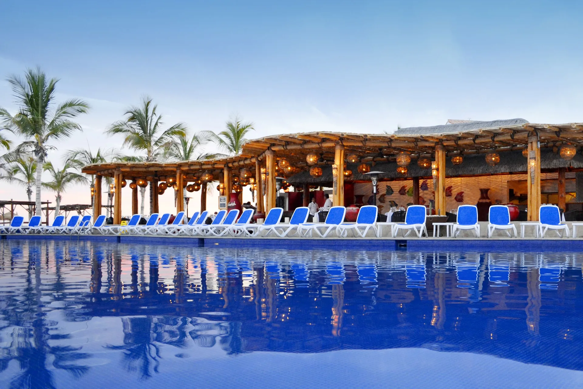 Poolside thatched bar with lounge chairs at Grand Decameron Los Cabos.