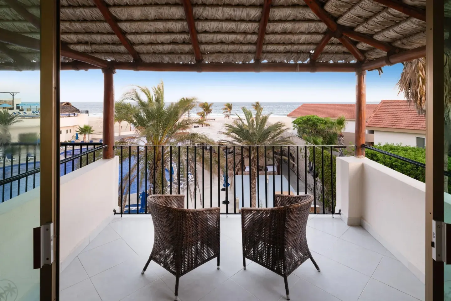 Ocean view balcony with two wicker chairs at Grand Decameron Los Cabos.