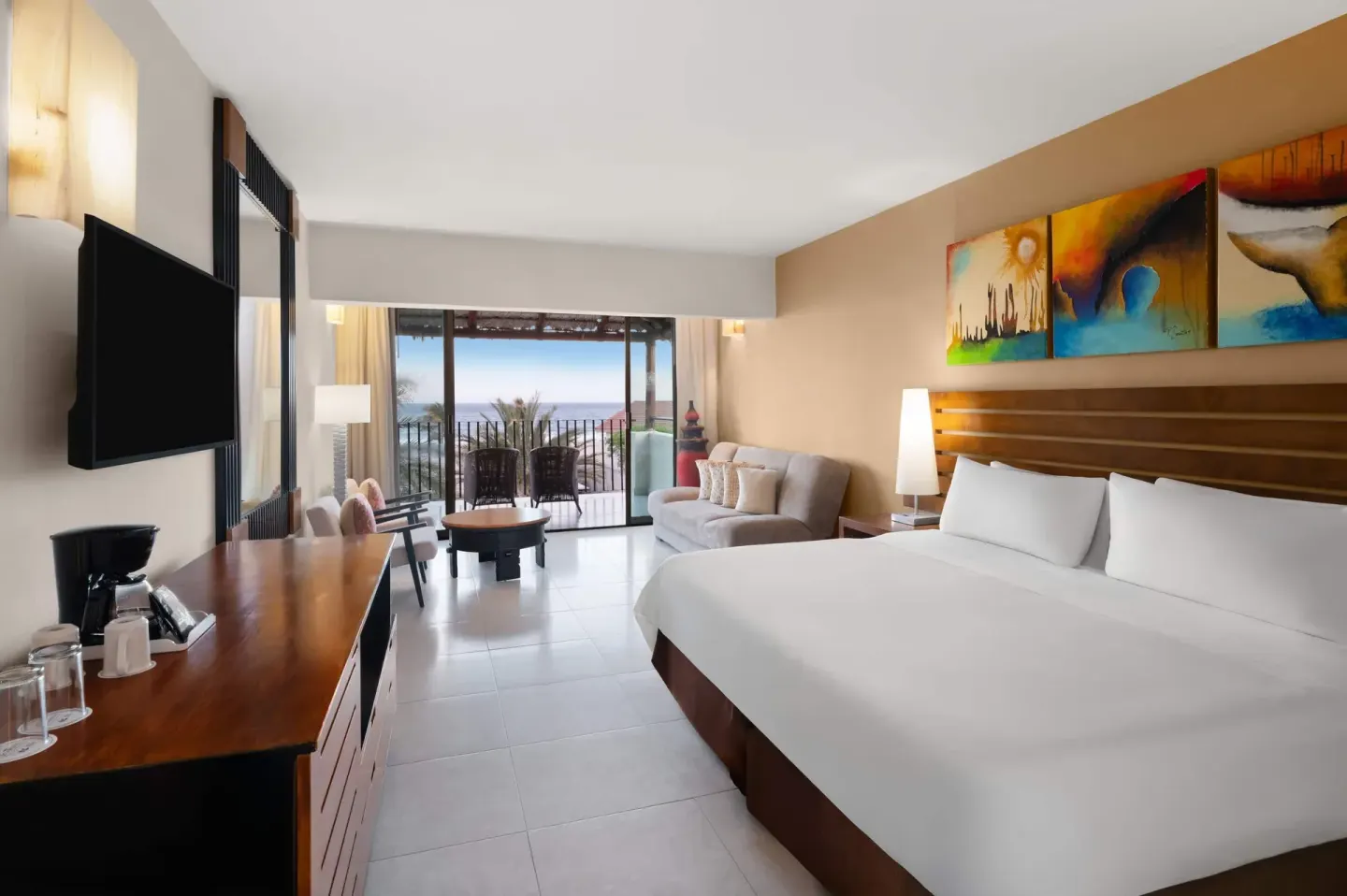 King-bed ocean view room with balcony seating at Grand Decameron Los Cabos.