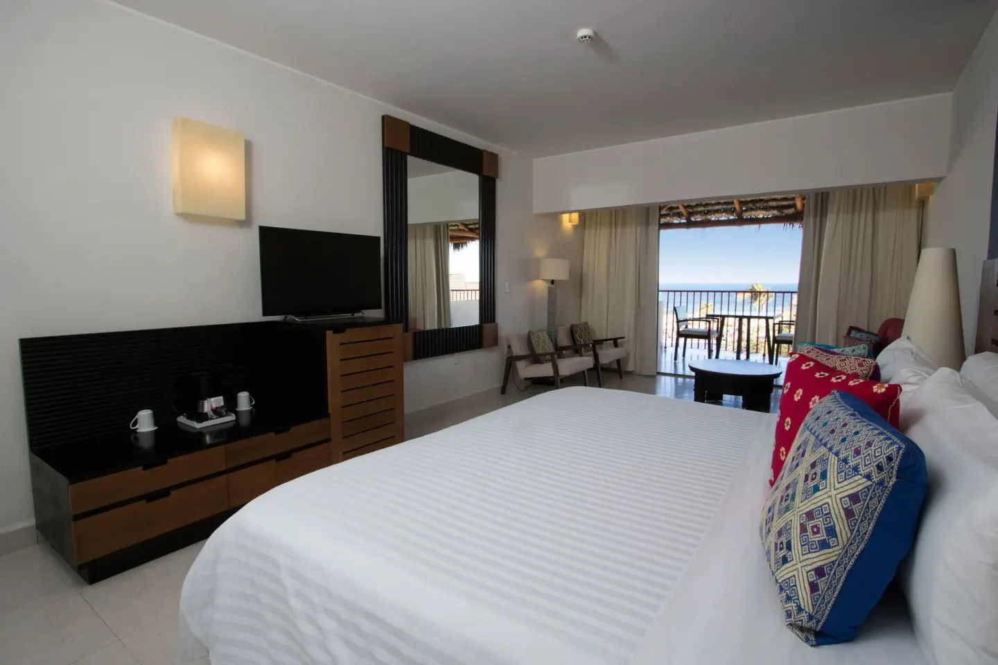 King-bed ocean view room with TV and balcony at Grand Decameron Los Cabos.