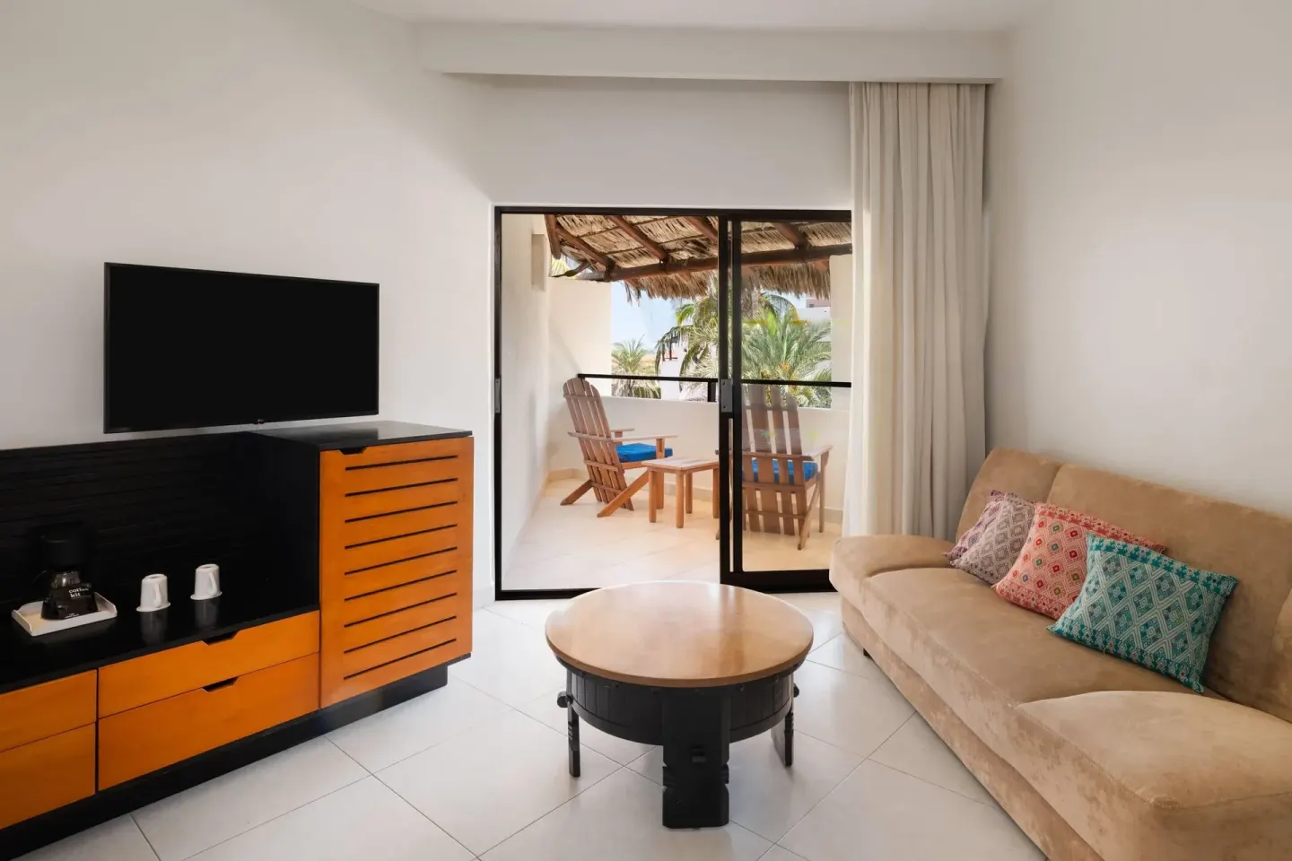 Ocean view room sitting area with sofa and balcony at Grand Decameron Los Cabos.