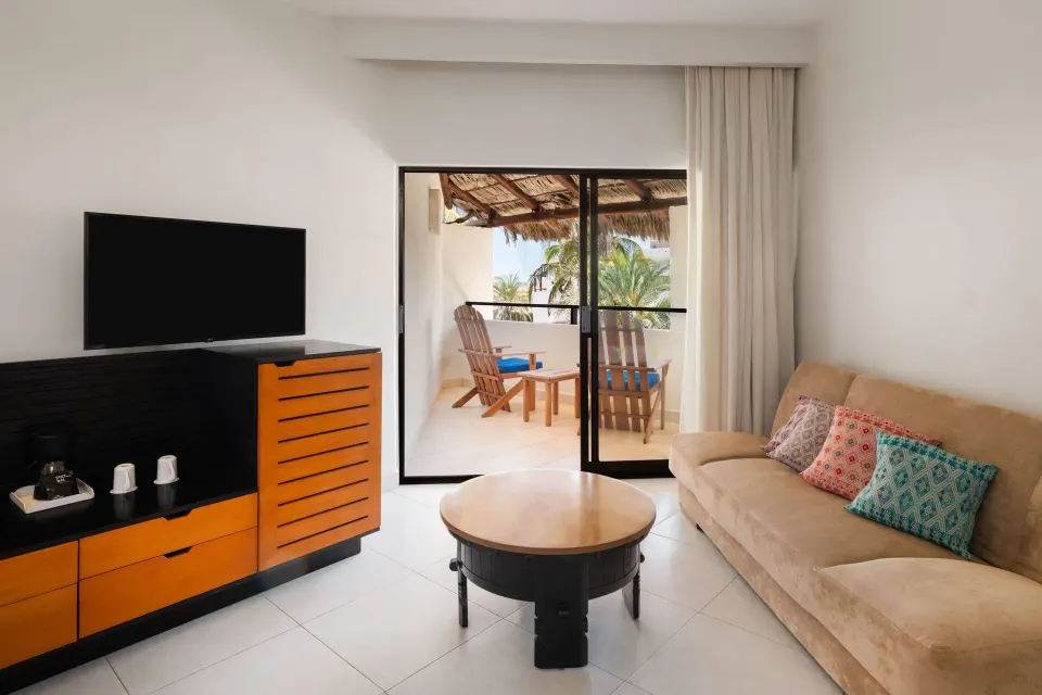 Ocean view room sitting area with sofa and balcony at Grand Decameron Los Cabos.