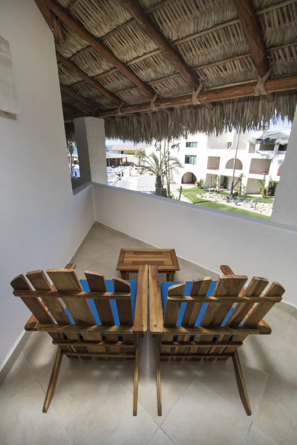 Ocean View room balcony seating under a thatched roof at Grand Decameron Los Cabos.