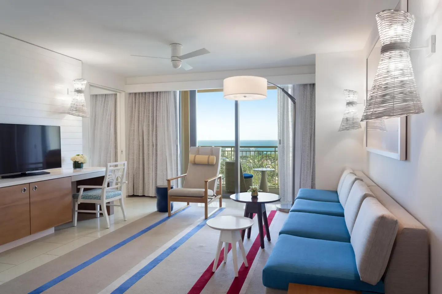 Suite sitting room with blue sofa and ocean-view balcony at Grand Hyatt Baha Mar.