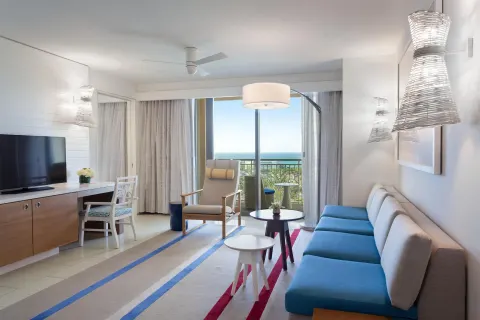 Suite sitting room with blue sofa and ocean-view balcony at Grand Hyatt Baha Mar.