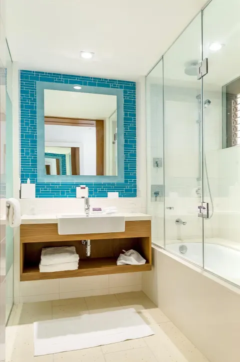Grand Room bathroom with blue tile mirror and shower-over-tub at Grand Hyatt Baha Mar.